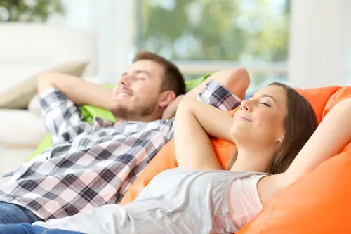 Couple or roommates relaxing lying on comfortable poufs in the living room at home.