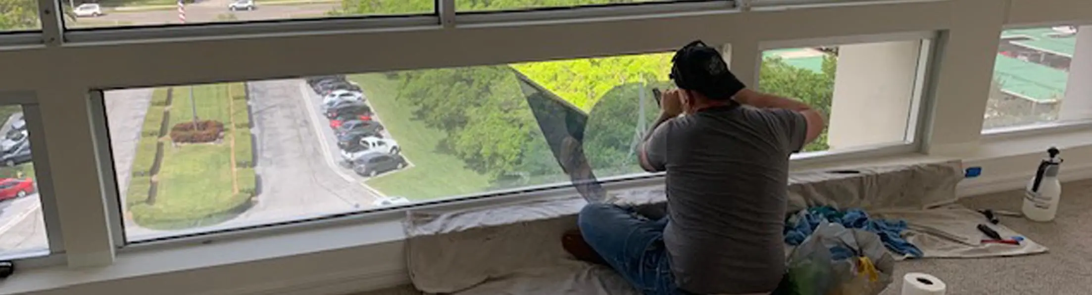 Man sitting on carpet installing window film.