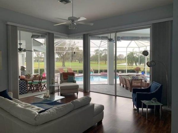 Window tint on living room sliders overlooking a lanai pool and golf course in a Florida home