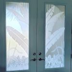 Frosted glass double doors with etched tropical leaf and plant designs on each panel, enhanced by decorative film for added elegance and privacy.