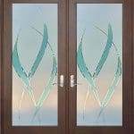 Double doors with frosted glass panels feature an abstract leaf-like design in teal and green, framed by dark wood and enhanced with decorative film for added privacy and style.