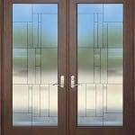 Double wooden doors with glass panels featuring a geometric frosted and clear design, enhanced by decorative film; silver handles are installed on each door.