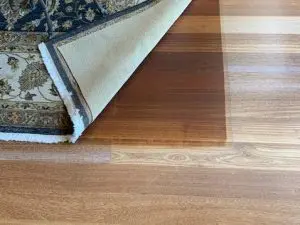 Carpet flipped up to show the less faded wooden floor underneath.