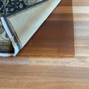 Carpet flipped up to show the less faded wooden floor underneath.