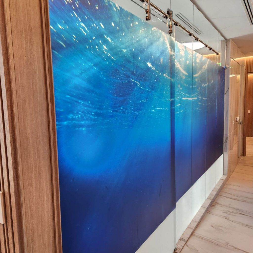 Full-color custom printed window film ocean mural covering glass panels in an office corridor