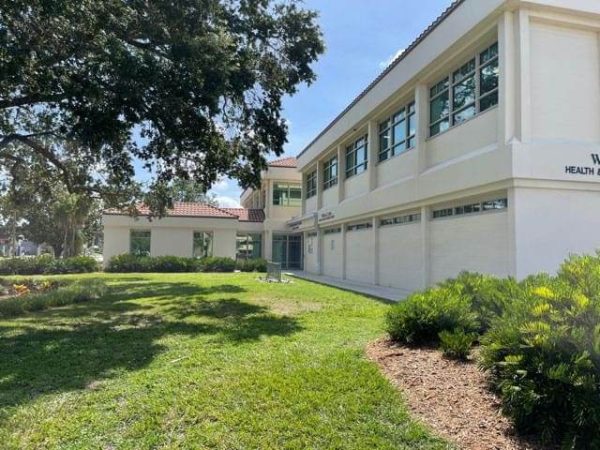 Reduce heat and glare (affinity 15) A two-story white building with multiple windows on a sunny day, surrounded by green grass and landscaping.