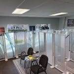 Showroom with display panels of frosted and patterned glass enhanced by 3M decorative film, two chairs, a small table with items on it, and signage promoting residential and local business services.