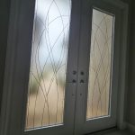Double front doors with frosted glass panels enhanced by 3M decorative film, featuring elegant curved line patterns that let light in while maintaining privacy.