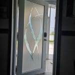 A white door with 3M decorative film on the frosted glass panels is open, revealing the porch and bright daylight outside. A "WELCOME" mat lies on the floor.