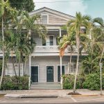 Key West style Florida home surrounded by palm trees in full sun