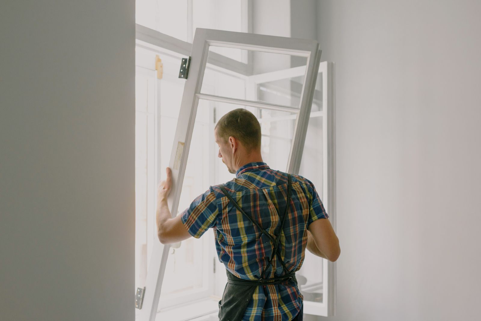 Installer fitting a new window, the kind of glass whose manufacturer warranty homeowners ask about before adding film